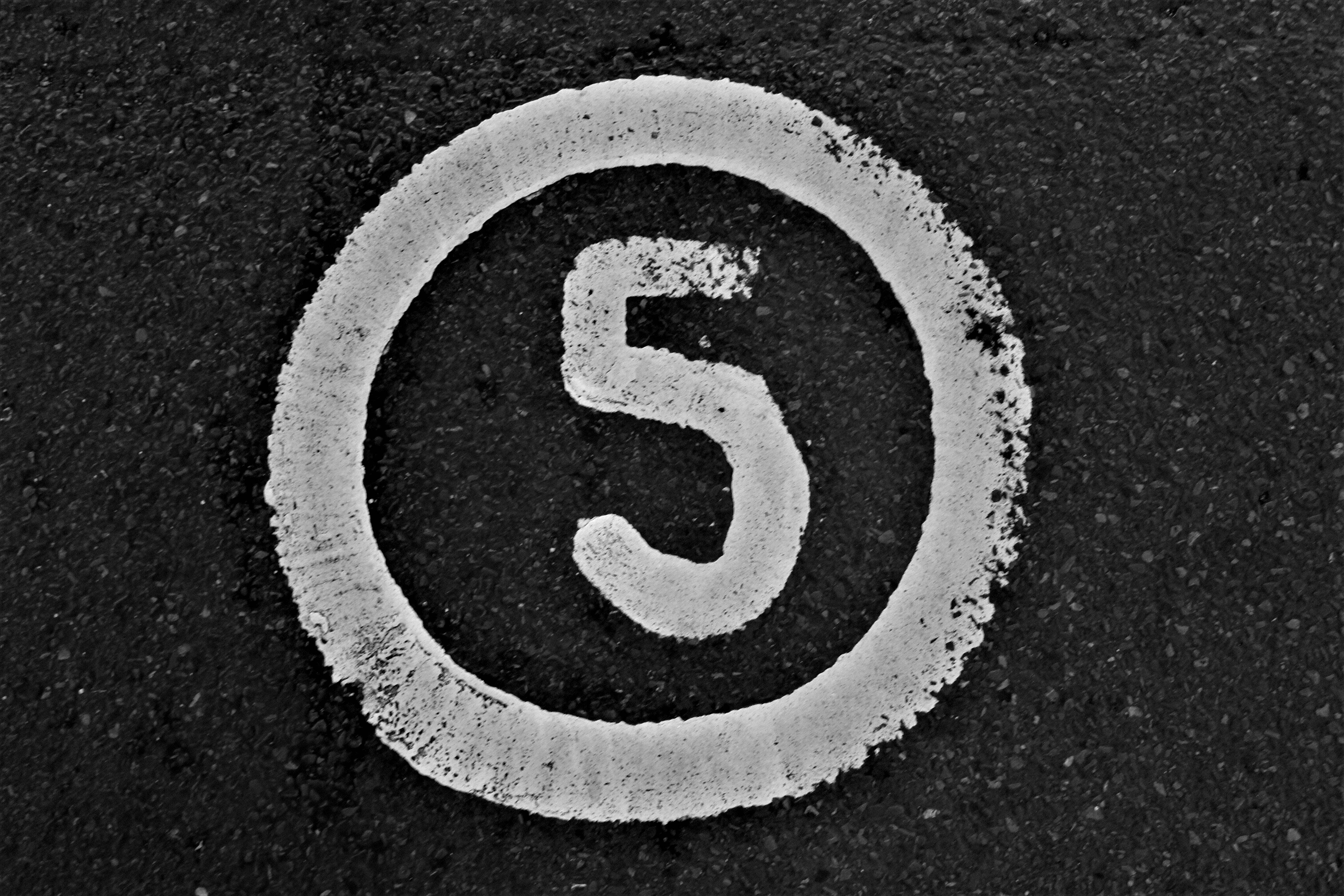 the number in 5 in white paint on black background